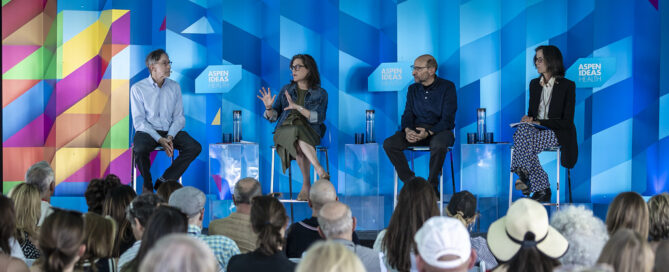 Food is Medicine panel on stage at Aspen Ideas Health 2025. They are seated on metal stools in front of a colorful backdrop. Far left, variations of wavering colors: orange, yellow, pink, green, blue, and purple. The rest of the backdrop are geometrical shapes in varying shades of blue with three prominent boxes with the title: Aspen Ideas Health in white lettering. Seated from left to right: Corby Kummer Executive Director, Food and Society Program, Aspen Institute Hilary Seligman Professor of Medicine, University of California San Francisco John Lumpkin President, Blue Cross and Blue Shield of North Carolina Foundation Wendy Slusser Associate Vice Provost, Semel Healthy Campus Initiative Center, University of California at Los Angeles